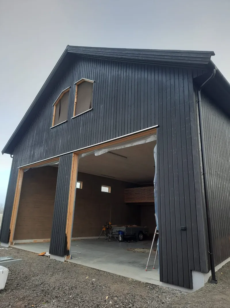 Ny garasje med sort stående kledning og to store portåpninger