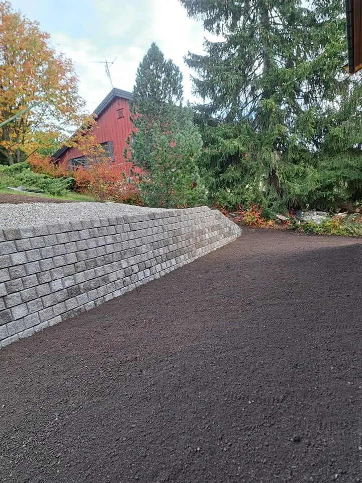 Støttemur i grå betongblokker langs et nyplanert uteområde