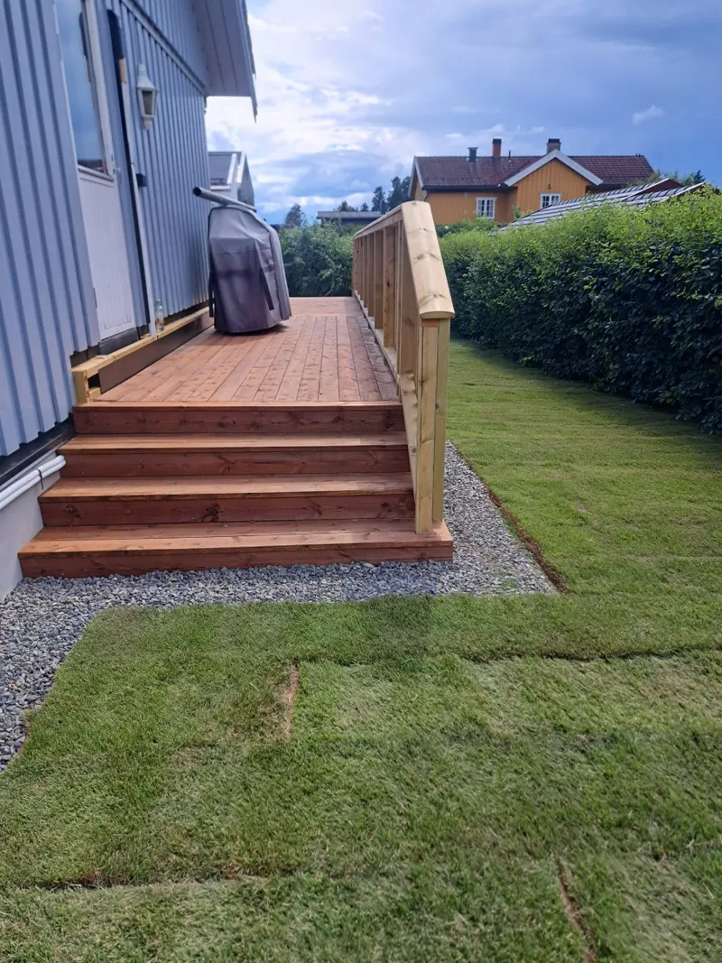 Trapp og terrasse langs husveggen, med pukk og ny plen langs hekken