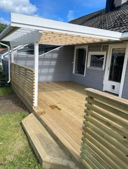 Ny terrasse med hvitt takoverbygg, levegg i spiler og trapp